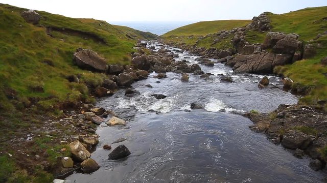 A small creek flows towards the ocean in the background