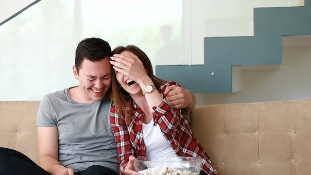 Couple Home Relaxing In Sofa And Watching Tv while eating popcorns