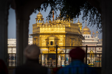 Silhouettes of two people in front of the Golden Temple in Amritsar, India