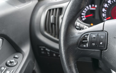 Fototapeta na wymiar media control buttons on the steering wheel in black leather, modern car interior details