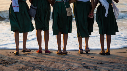 Fototapeta na wymiar Group of girls standing in font of the waterline of the ocean at Cochin Beach, India