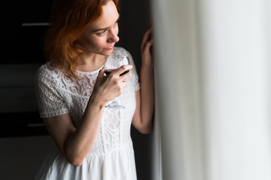 Woman drinking wine at window