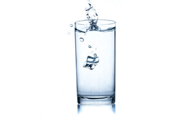 Glass of water with ice cube on white background.
