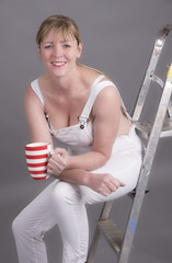 Worker wearing dungarees taking a tea break at her place of work