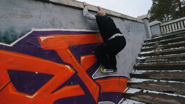 Urban city parkour - slow motion jumping - athlete performing free-running in winter park