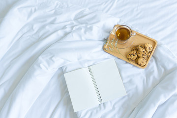 Cookies and tea on the bed and blank notebook