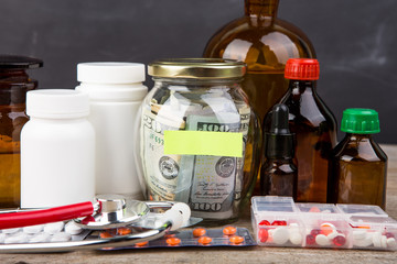 Obraz na płótnie Canvas Saving money for health care insurance - money glass, stethoscope, pills and bottles