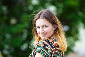 Fototapeta premium Smiling woman portrait on the blurred green foliage background. Selective focus.