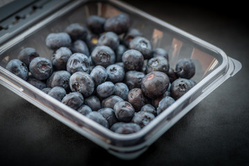 Natural looking blueberries in plastic container. Selective focus.