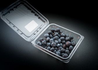 Natural looking blueberries in plastic container. Selective focus.