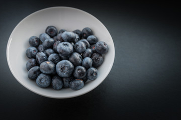 Natural looking blueberries in white cup. Selective focus.