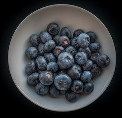 Natural looking blueberries in white cup. Selective focus.