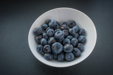 Natural looking blueberries in white cup. Selective focus.