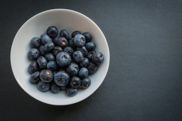 Natural looking blueberries in white cup. Selective focus.