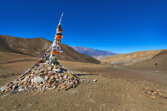 Traditional Tibetan pile of stones and colored flags on the pass in Mustang region of Himalayas, Nepal