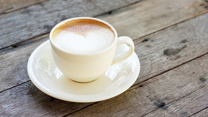 Hot coffee in a white cup on a wooden table.