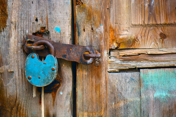 Old rusty padlock hanging on an old wooden door