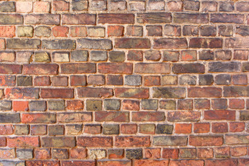 Old empty uneven raw varied color brick wall