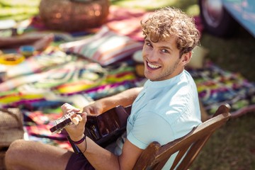 Portrait of happy man playing guitar in park