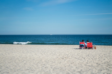 Fototapeta na wymiar Couple in Chairs by the Beach – Summer in the Hamptons, USA