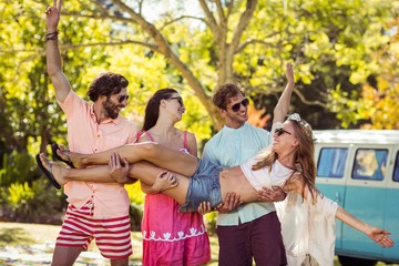 Group of friends carrying a women in park