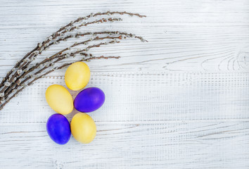 Yellow and purple Easter eggs and willow twigs on a white background. Concept Happy Easter.
