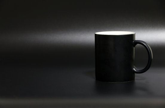 black cup Coffee on the black desk in studio.Copy space