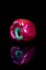 A single red sweet bell pepper with reflection