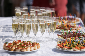 glasses with champagne. catering banquet table. a lot of snacks and canapes