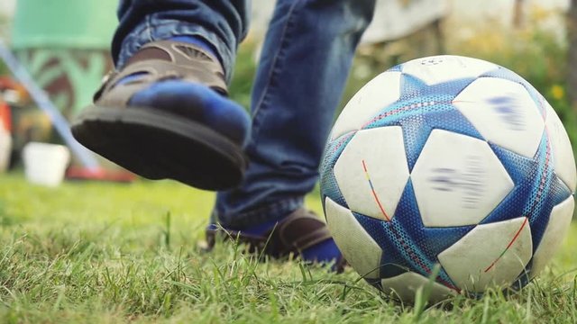 Close up of young boy's legs playing with soccer ball kicks on the grass in summer sunny day in slow motion. 1920x1080