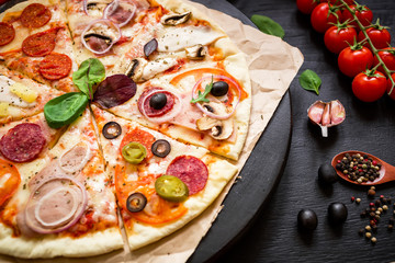 Pizza with ingredients and spices on black background. Flat lay, top view.