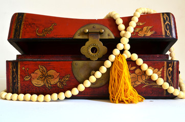 A vintage beautiful jewelry box and a string of beads on it.