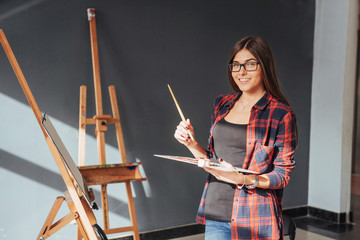 Young woman artist painting a picture in studio