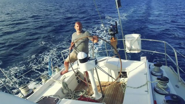 man on steering wheel navigating sail boat