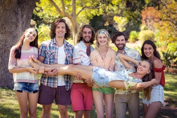Group of friends lifting woman at campsite