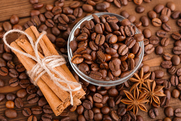 Coffee beans and cinnamon on a background of burlap. Roasted coffee beans background close up. Coffee beans pile from top with copy space for text. Seasoning. Spice. Cinnamon. Badian. Coffee house.