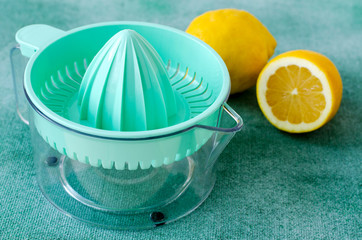 Fresh lemons with citrus squeezer on turquoise background. Copy space
