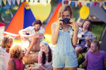 Portrait of woman taking a picture of friends at campsite
