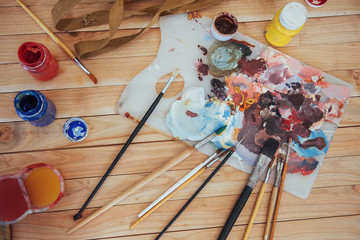 The artist's palette. Colored oil paints over a pallete on a table.