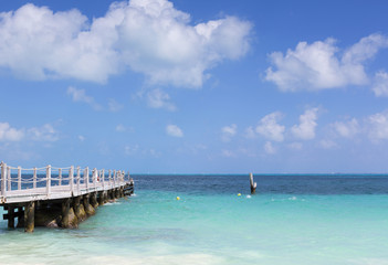 Long wooden dock on the shore of the Caribbean sea.