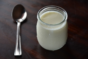 yogurt in a jar with a silver spoon on a wooden table