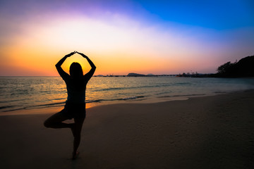 Silhouette woman yoga on the beach over the sunset