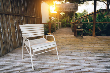 White wooden chair in bamboo hut at the garden in selective focus with warm fall color in the morning.