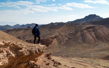 Fototapeta premium Climber over a canyon. Man standing on a rocky cliff over the Valley of Castles in the Sharyn Canyon National Park, Kazakhstan. Early spring sunny day.