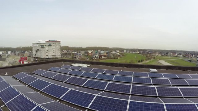Aerial flight low altitude and backwards bird view over sustainable roof of modern building with solar panels designed to absorb sun's rays as source of energy for generating electricity or heating 4k