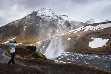 Photographer on Skogafoss facing the Strong winds, which strong enough to reversed the waterfall direction.