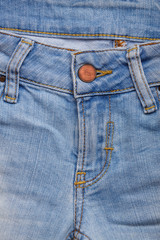 Fototapeta premium Denim jeans texture background with torn. The texture of the colored cotton fabric. Stitched texture jeans background. Fashion jeans button. Pocket and rivet on jeans. Fiber and fabric structure.