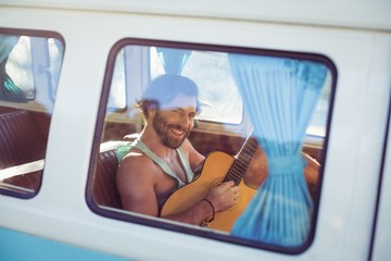 Naklejka premium Man playing guitar in campervan