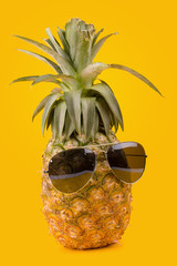 Trendy glasses summer pineapple wearing hipster style on yellow background.