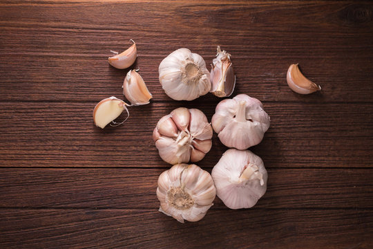 Garlic and garlic press on rustic wooden board.
